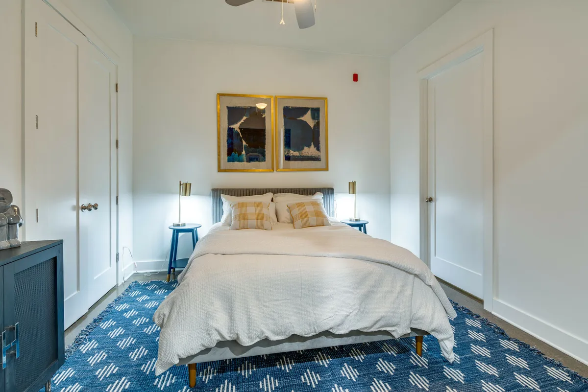 A serene bedroom with a neatly made bed, elegant artwork above the headboard, and matching nightstands on both sides. The room exudes a peaceful environment perfect for winding down after a busy day.